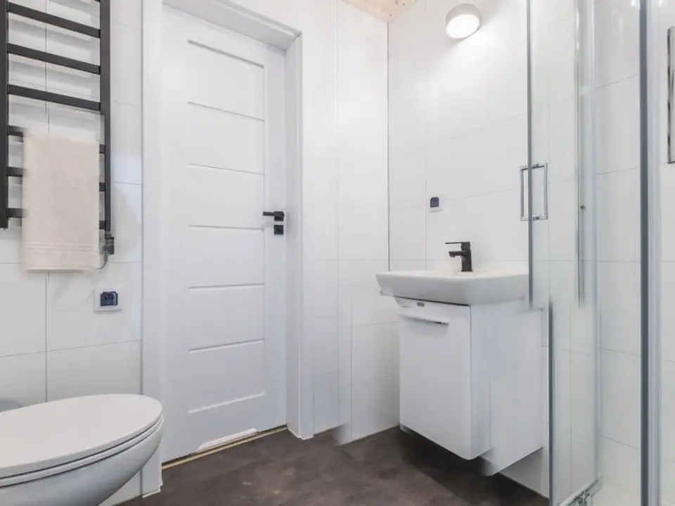Bad des Modulhauses TINY-MAX 35-1 mit Dusche, Waschtisch mit Unterschrank, WC und schwarzem Handtuchheizkörper. Visualisierung